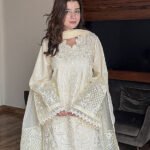 Model wearing Iznik 3-piece heavy embroidered off-white lawn suit with organza dupatta and lace trousers lubaba luxury.