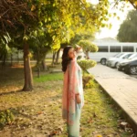 Woman wearing a Minha 3-piece grip silk suit in pastel blue with pink floral embroidery and a matching chiffon dupatta lubaba luxury.