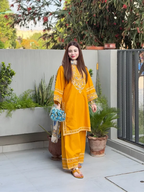 A mustard yellow 3-piece embroidered cotton suit with a Munaar dupatta, featuring white lace detailing on the sleeves and hem Lubaba Luxury.
