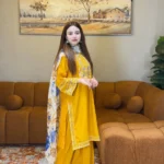 A mustard yellow 3-piece embroidered cotton suit with a Munaar dupatta, featuring white lace detailing on the sleeves and hem Lubaba Luxury.