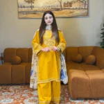 A mustard yellow 3-piece embroidered cotton suit with a Munaar dupatta, featuring white lace detailing on the sleeves and hem Lubaba Luxury.