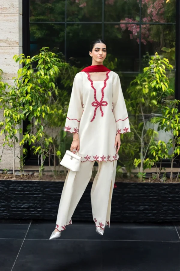 Ivory cotton Pakistani 3-piece suit with red bow embroidery and red dupatta by Lubaba Luxury.
