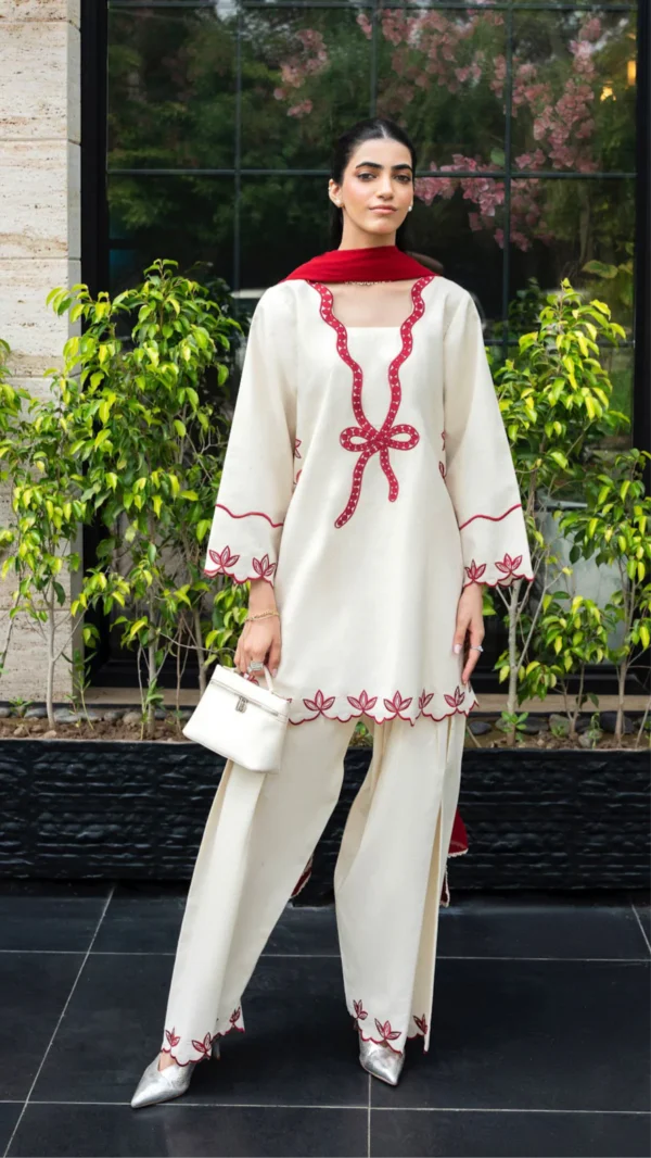 Ivory cotton Pakistani 3-piece suit with red bow embroidery and red dupatta by Lubaba Luxury.