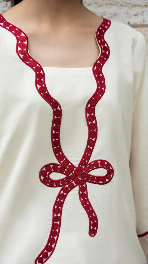 Ivory cotton Pakistani 3-piece suit with red bow embroidery and red dupatta by Lubaba Luxury.