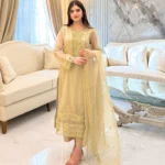 Woman wearing a gold embroidered organza 3-piece Pakistani suit by Lubaba Luxury.