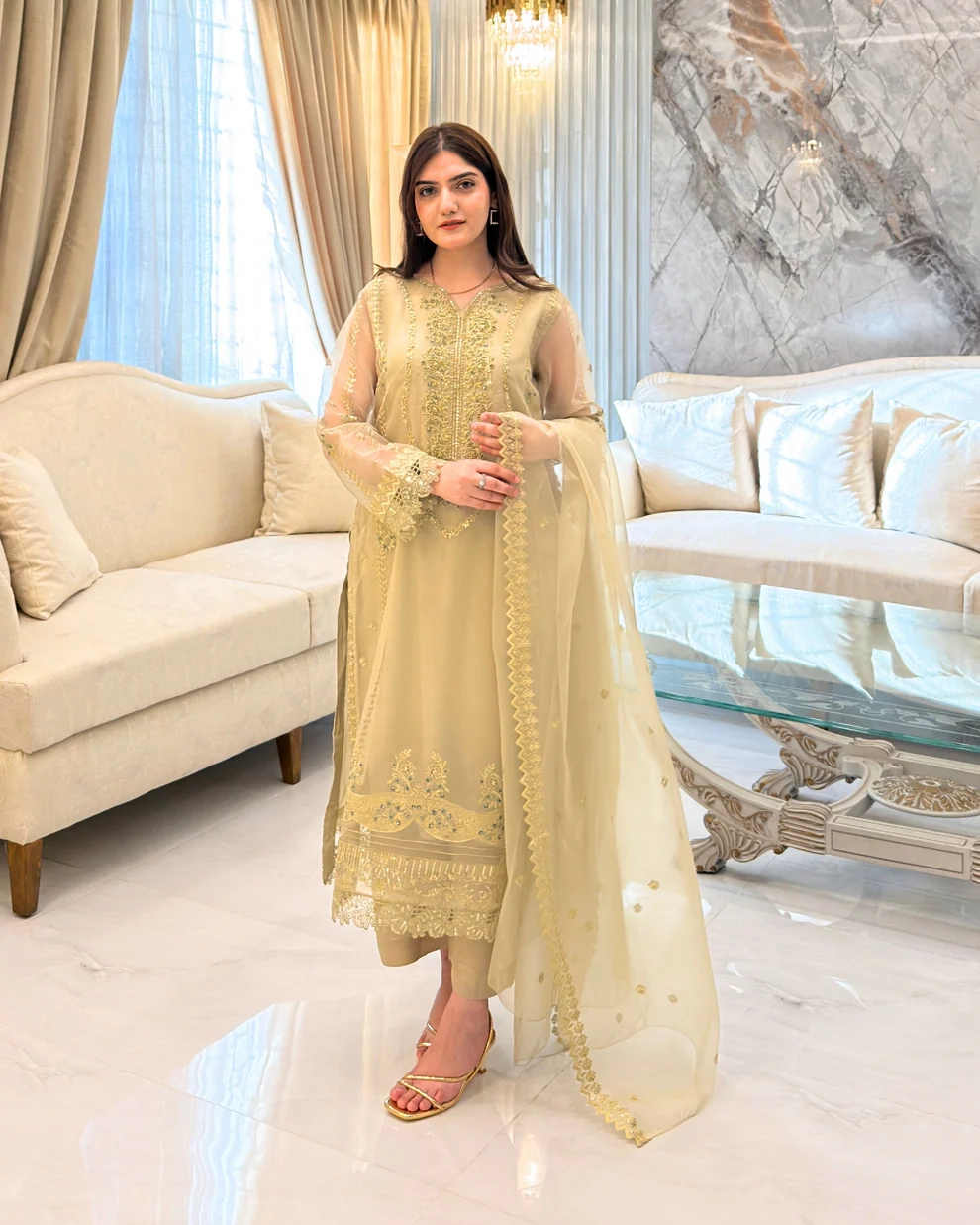 Woman wearing a gold embroidered organza 3-piece Pakistani suit by Lubaba Luxury.