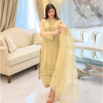 Woman wearing a gold embroidered organza 3-piece Pakistani suit by Lubaba Luxury.