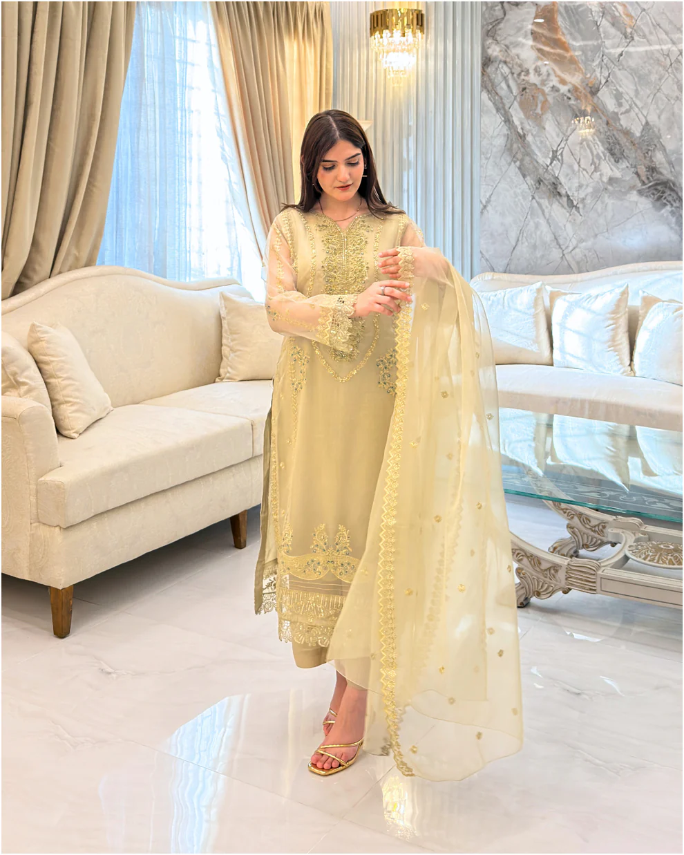 Woman wearing a gold embroidered organza 3-piece Pakistani suit by Lubaba Luxury.