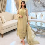 Woman wearing a gold embroidered organza 3-piece Pakistani suit by Lubaba Luxury.