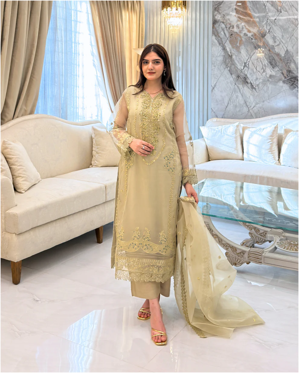 Woman wearing a gold embroidered organza 3-piece Pakistani suit by Lubaba Luxury.