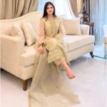 Woman wearing a gold embroidered organza 3-piece Pakistani suit by Lubaba Luxury.