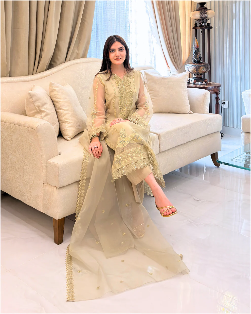 Woman wearing a gold embroidered organza 3-piece Pakistani suit by Lubaba Luxury.