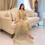 Woman wearing a gold embroidered organza 3-piece Pakistani suit by Lubaba Luxury.