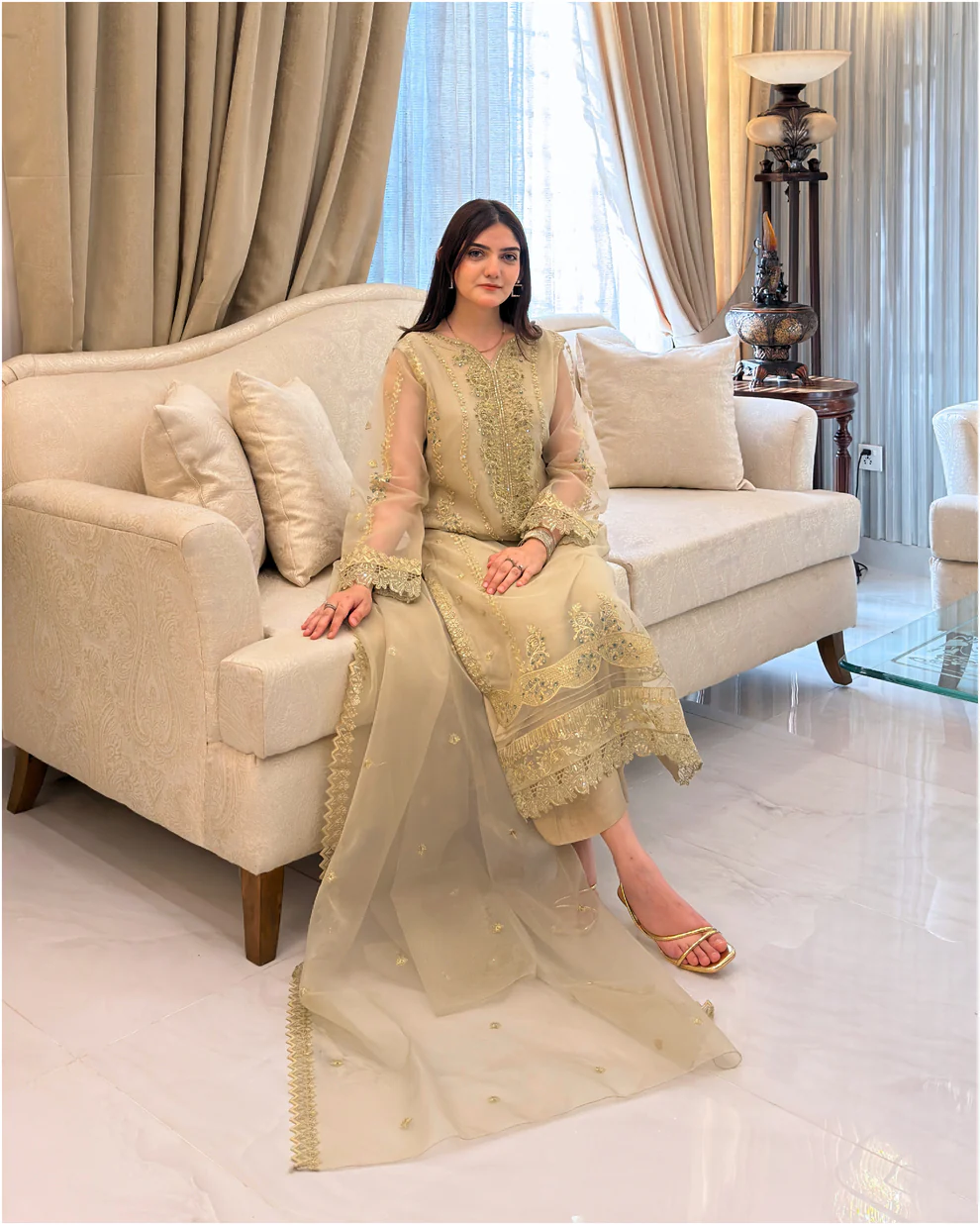 Woman wearing a gold embroidered organza 3-piece Pakistani suit by Lubaba Luxury.